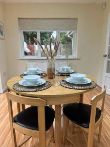 a wooden table with chairs and plates on it at Real Lush Properties-New Home Sleeps 12-Business & Relocation-Free Parking in Dudley