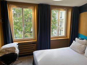 a bedroom with a bed and two windows at Appartement Censier Daubenton in Paris