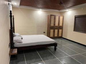 um quarto com uma cama no canto de um quarto em Ooru em Udupi