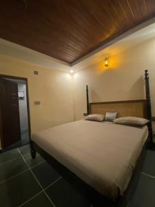 1 dormitorio con 1 cama grande y cabecero de madera en Ooru, en Udupi