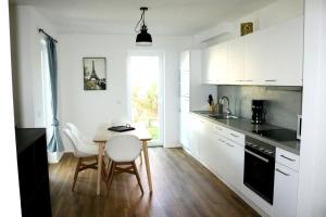 een keuken met witte kasten en een tafel en stoelen bij Work & Stay Apartment Ingolstadt in Ingolstadt