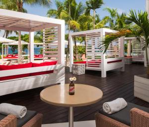 un patio con mesas, sillas y palmeras en S Hotel Montego Bay - Luxury Boutique All-Inclusive Hotel, en Montego Bay