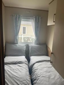 two beds in a small room with a window at 87 Lancaster Crescent in Tattershall