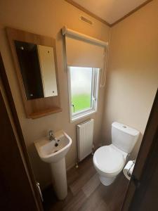 a bathroom with a toilet and a sink and a window at 87 Lancaster Crescent in Tattershall