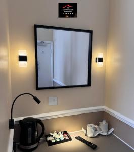 a mirror on a wall above a desk with a coffee maker at The Commongate Hotels in London