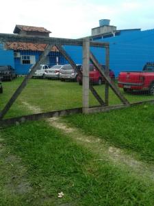 una recinzione di legno in un campo con auto in un parcheggio di Residencial Água Azul a Capão da Canoa