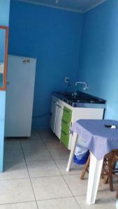 een keuken met een tafel, een wastafel, een tafel en een koelkast bij Residencial Água Azul in Capão da Canoa