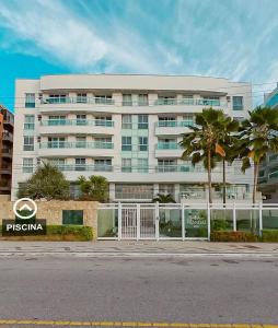 a large white building with palm trees in front of it at MANDAI APART in Cabo Frio
