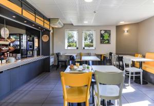 une salle à manger avec des tables et des chaises jaunes dans l'établissement B&B HOTEL Dijon Nord Zénith, à Dijon