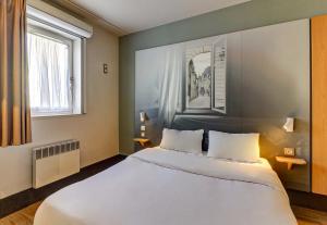 a bedroom with a large white bed and two windows at B&B HOTEL Dijon Nord Zénith in Dijon