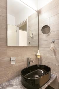 a bathroom with a large black sink and a mirror at Marina Apartments in Kokkari