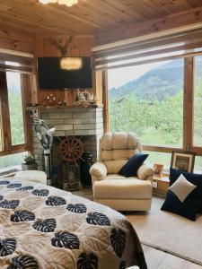 a bedroom with a bed and a chair and a large window at Chalet Shanag Manali in Manāli