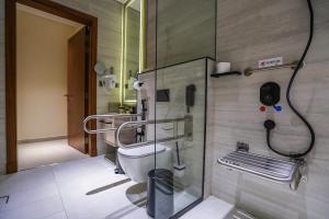 a bathroom with a toilet and a phone on the wall at Vivian Park El Raeid Hotel in Riyadh
