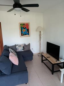 a living room with a blue couch and a tv at Newly Renovated Seaside Oasis at Bonita Village in Las Terrenas