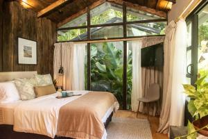 a bedroom with a bed in front of a large window at KAÑIK APART HOTEL in Puerto Viejo