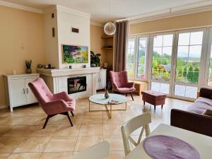 sala de estar con sillas rosas y chimenea en Lakeside Home, en Ryn