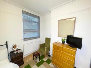 een slaapkamer met een bed en een tv op een dressoir bij E-Sky Homes in South Norwood
