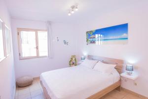 a white bedroom with a bed and a window at Esquinzo Sunrise in Playa Jandia