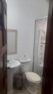 a white bathroom with a toilet and a sink at Hotel Casa la Gregorienne in La Vega
