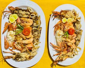 two plates of food with shrimp and pasta on a table at The Kingslayer Resort in Negombo