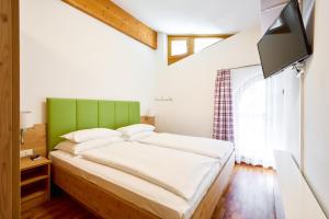 um quarto com uma cama com uma cabeceira verde e uma televisão em Alpina Holiday Living Apartments em Obertauern