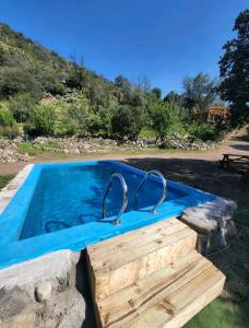 a swimming pool with a stone wall and a blue swimming poolvisor at Arte Vitral Lodge - 4camas- aislada- terrazas -vista - piscina-sauna in Guayacán