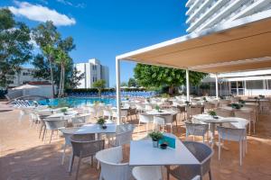 een restaurant met tafels en stoelen en een zwembad bij HSM Atlantic Park in Magaluf