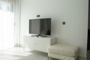 a tv sitting on top of a white cabinet with a chair at Seaside Serenity in Bodrum: Luxury Retreat w View in Turgutreis