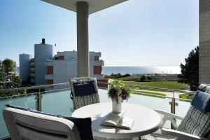 una mesa y sillas en un balcón con vistas al océano en Villa am Hang Wohnung 11 en Grömitz