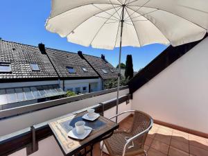 a balcony with a table and an umbrella at Ferienhaus Can Miguel - Urlaubsoase in ruhigem Wohngebiet in Lindau-Bodolz