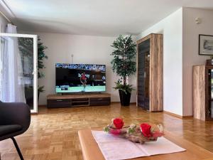 una sala de estar con TV y una mesa con flores. en Ferienhaus Can Miguel - Urlaubsoase in ruhigem Wohngebiet, en Lindau-Bodolz