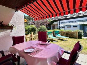 una mesa rosa y sillas bajo una sombrilla roja en Ferienhaus Can Miguel - Urlaubsoase in ruhigem Wohngebiet, en Lindau-Bodolz