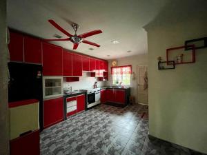 a kitchen with red cabinets and a ceiling fan at K & J Homestay — Seremban Jaya 7 in Seremban