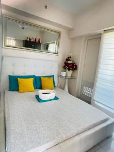 1 dormitorio con 1 cama grande con almohadas amarillas y azules en 9th floor Taal View with 2 Balconies w/ Fiber Net, en Tagaytay