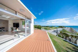 a house with a deck with a view of the ocean at クリスタルヴィラ南城 in Azama