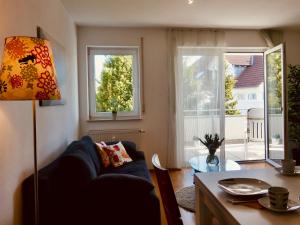 - un salon avec un canapé bleu et une table dans l'établissement Ferienwohnung Bodenseele - Wohlfühloase mit großem Sonnenbalkon, à Langenargen