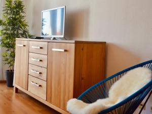 Ein Fernseher auf einer Kommode mit zwei blauen Stühlen. in der Unterkunft Ferienwohnung Bodenseele - Wohlfühloase mit großem Sonnenbalkon in Langenargen