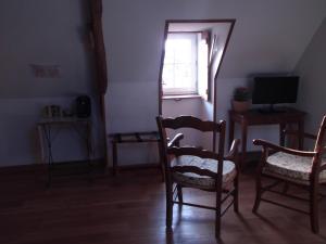 a room with chairs and a television and a window at Le Clos des Tilleuls D Day Home, Chambres d'hôtes, Suite avec Sauna Privatif, Suite avec balnéothérapie privative, en supplément option SPA bain à remous in La Vendelée