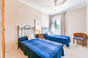 a bedroom with two beds and a chair and a window at Villa Angeles Tur in Calpe
