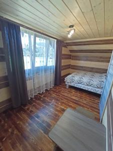 Cette chambre comprend un lit et une grande fenêtre. dans l'établissement Girskyi Kutochok, à Verkhovyna