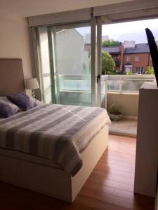 a bedroom with a bed and a view of a balcony at Zona Güemes. Piscina climatizada. Hermoso 2 amb. in Mar del Plata