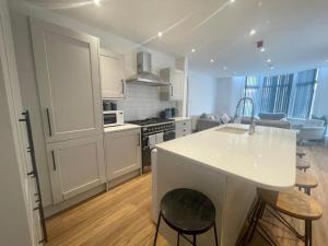 a kitchen with white cabinets and a kitchen island with stools at Beach House By Sasco in Blackpool