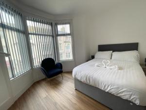 a bedroom with a bed and a chair and windows at Beach House By Sasco in Blackpool