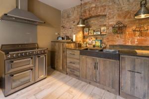a kitchen with wooden cabinets and a brick wall at Altes Fotohaus in Freyburg +4 photos