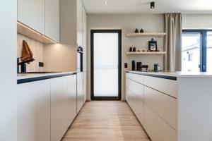 a kitchen with white cabinets and a hallway with a door at Tiny Villa mit Pool im Salzburger Seenland in Kirchberg bei Mattighofen