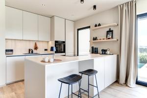 a kitchen with white cabinets and two bar stools at Tiny Villa mit Pool im Salzburger Seenland in Kirchberg bei Mattighofen