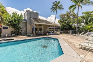 a swimming pool in front of a house with palm trees at Kailua Bay Resort 4-303 in Kailua-Kona