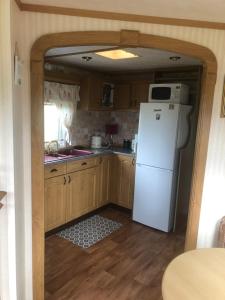 a kitchen with a white refrigerator and a microwave at Màire’s Mobile Home in Falcarragh