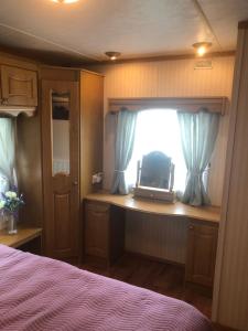 a bedroom with a bed and a window with a laptop at Màire’s Mobile Home in Falcarragh