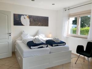 a white bedroom with a bed with towels on it at Ferienwohnung Im Vogelsang in Sigmarszell